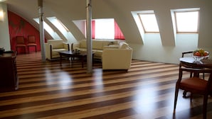 Un loft amplio con techo inclinado, un sofá, una mesa de comedor con fruta y una pared de acento roja.