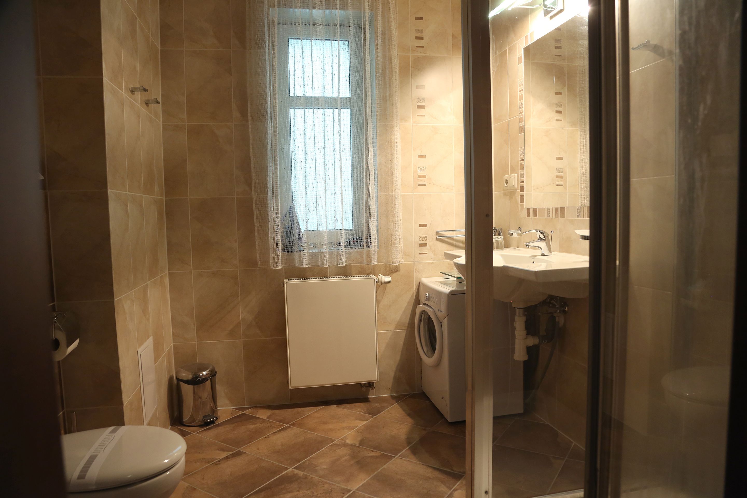 A compact bathroom with a toilet, washing machine, and sink.