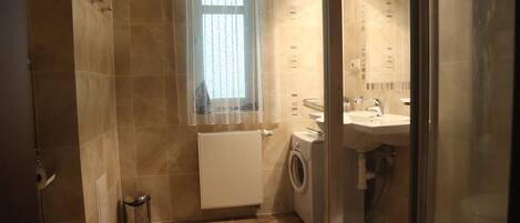 A compact bathroom with a toilet, washing machine, and sink.