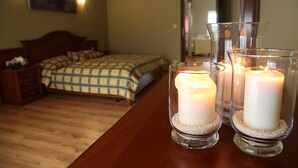 Un dormitorio con una cama, mesitas de noche y una mesita auxiliar. Hay velas en candelabros sobre una mesa de madera.