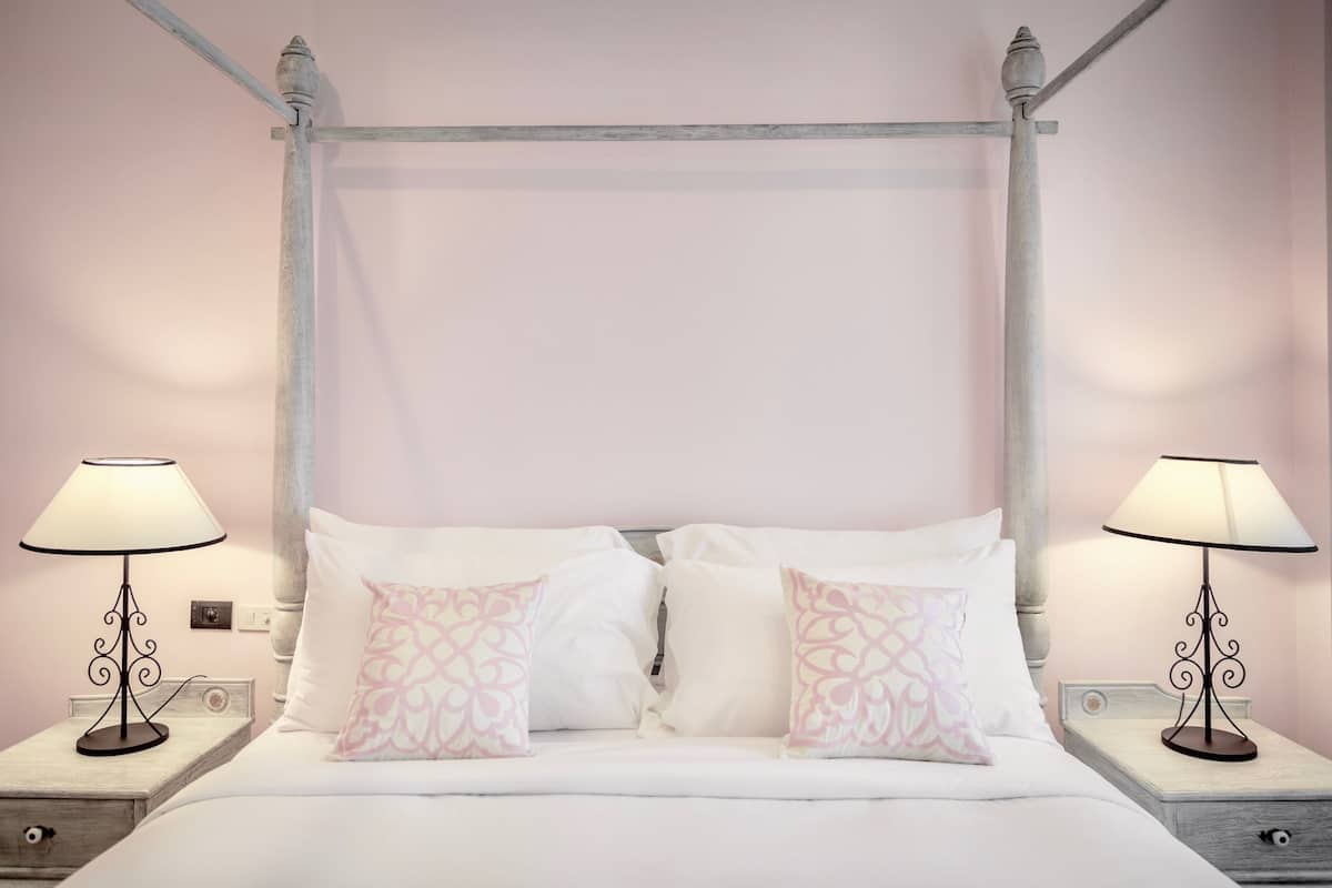 A bed with a canopy, two bedside tables with lamps, and patterned pillows.