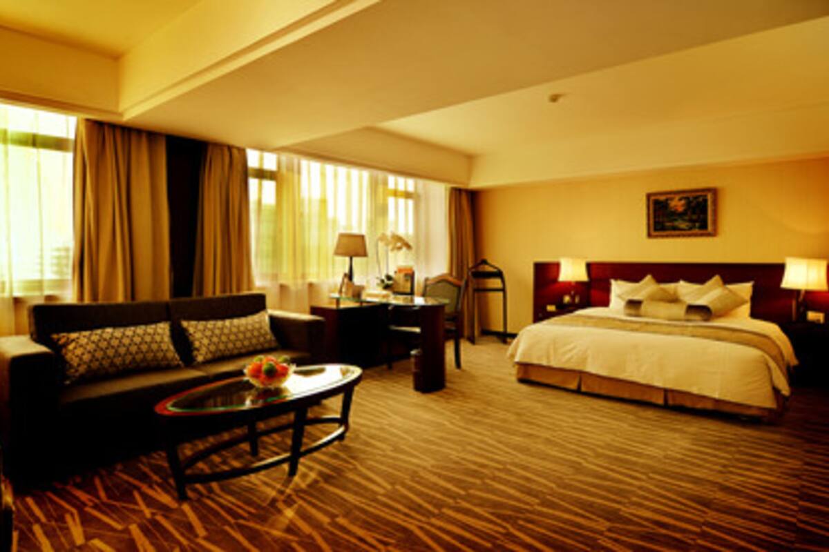 A hotel room with a large bed, a sofa, a coffee table, and a desk.