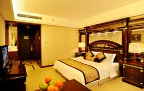 A hotel room with a large bed, a desk with a television, and a fruit bowl on the floor. - Sovereign Hotel KunShan (Suzhou)