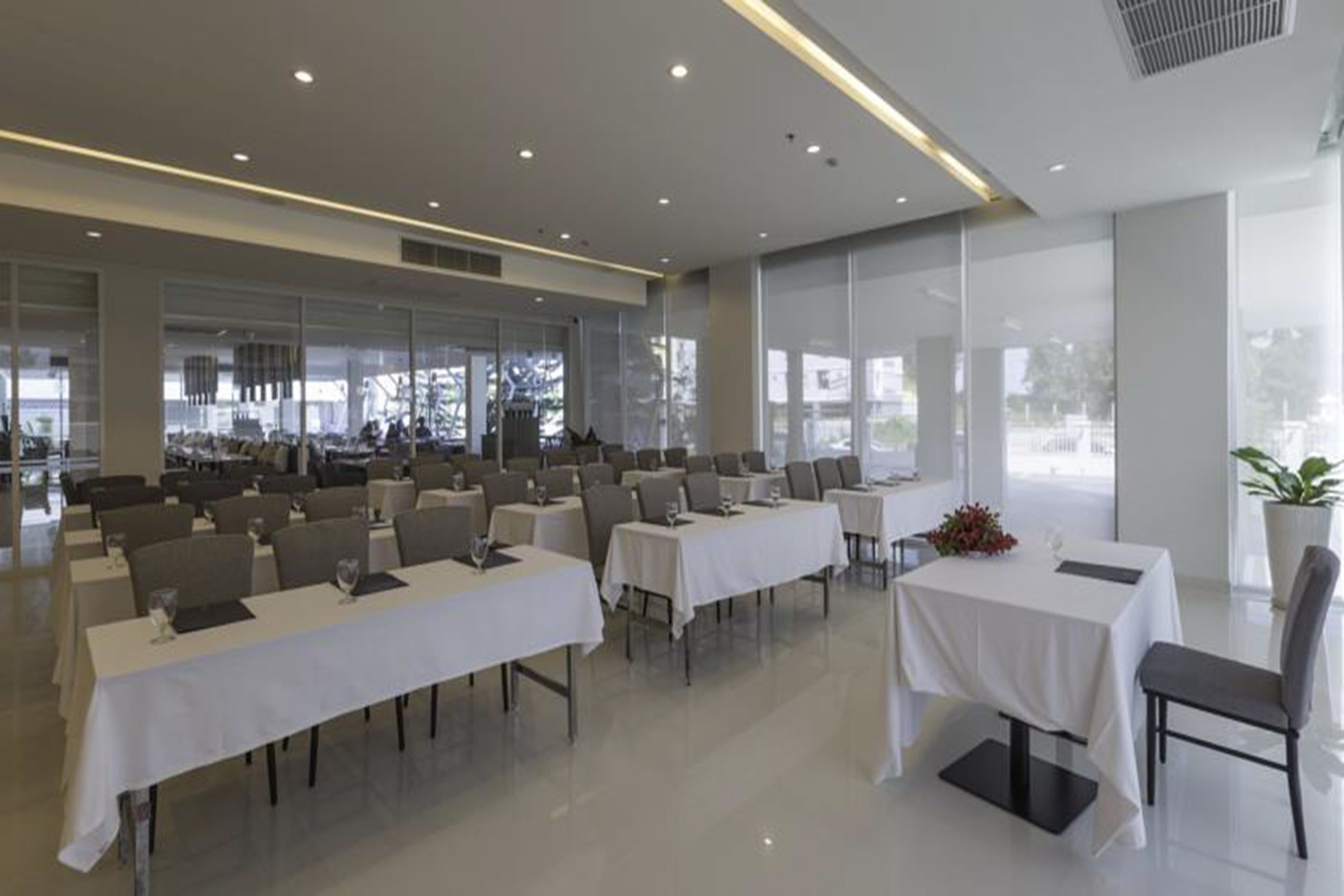 Un'area ristorazione moderna con diversi tavoli e sedie, ampie finestre e un design pulito e minimalista.