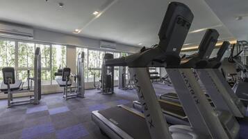 A gym with treadmills, weight machines, and a large window providing natural light.