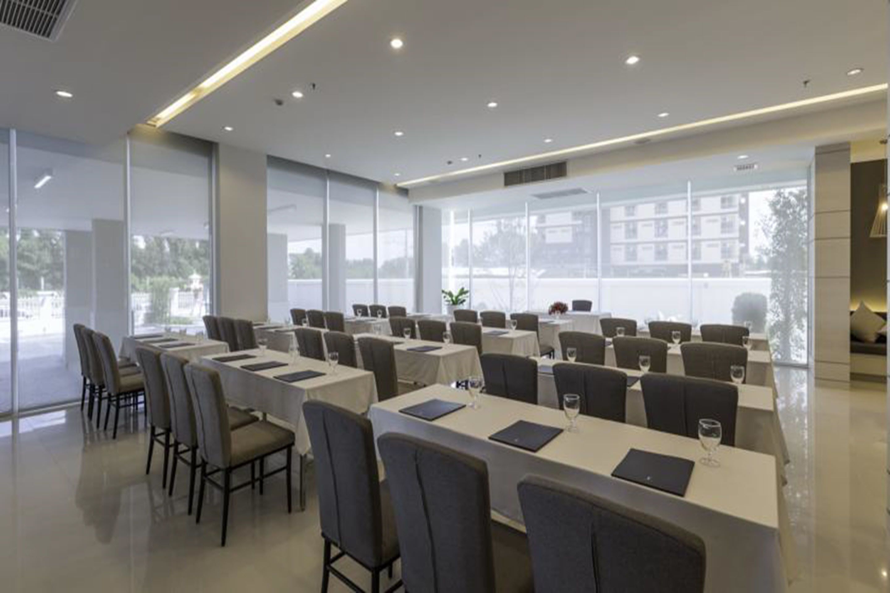 A modern conference room with long tables and chairs, large windows, and a clean, minimalist design.