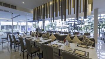 A modern restaurant with high tables and comfortable seating, large windows offering a view of the cityscape.