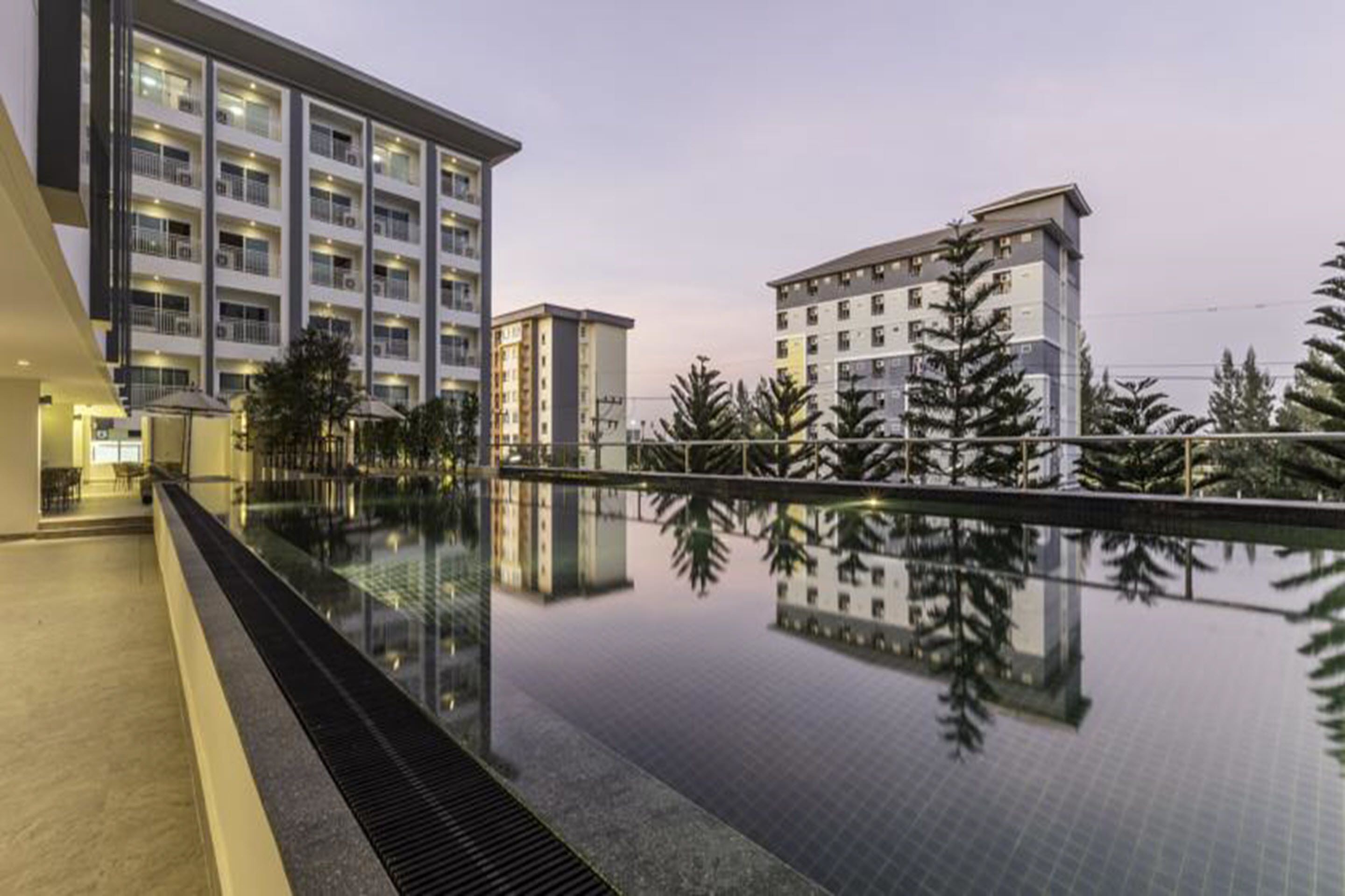 Un hôtel moderne doté d’une grande piscine, de plusieurs étages et d’un espace extérieur bien aménagé avec des arbres.
