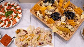 A variety of cheeses, grapes, and walnuts on a wooden board.