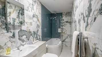 Une salle de bain avec un lavabo blanc, des toilettes, une baignoire et une douche.