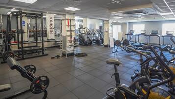 A gym with various exercise equipment including treadmills, weight machines, and a squat rack.
