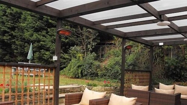 Un área de patio al aire libre con mobiliario de mimbre y techo de vidrio.