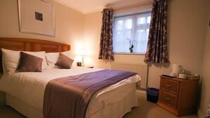 Un dormitorio ordenado con cama, mesita de noche y cómoda.