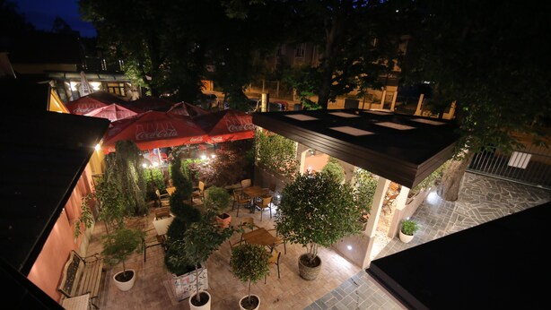 Een terras met tafels en stoelen, plantenbakken en parasols.