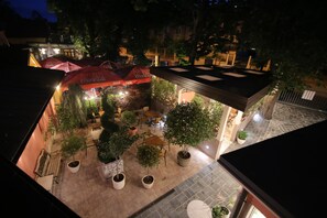 An outdoor café area with tables and chairs, potted plants, and umbrellas. - Boutique Hotel Asteria (Ljubljana)