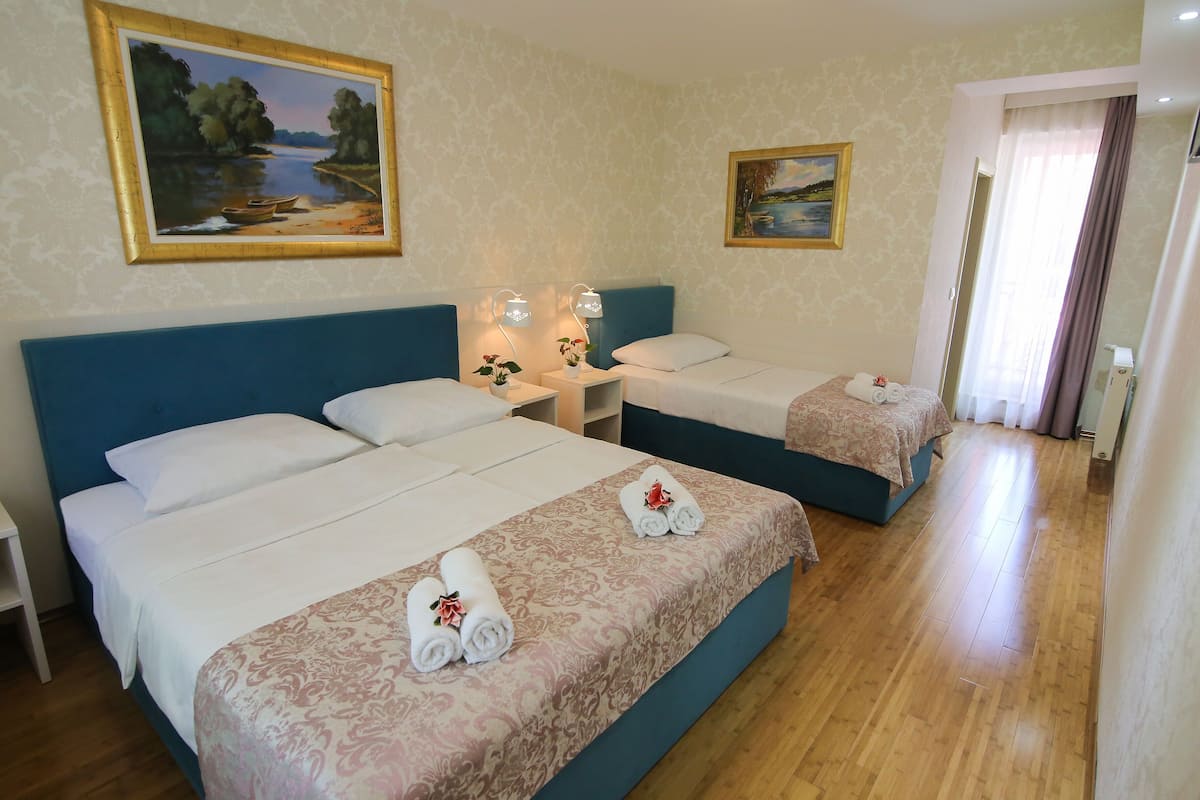 A hotel room with two beds, a nightstand with lamps, and a painting on the wall.