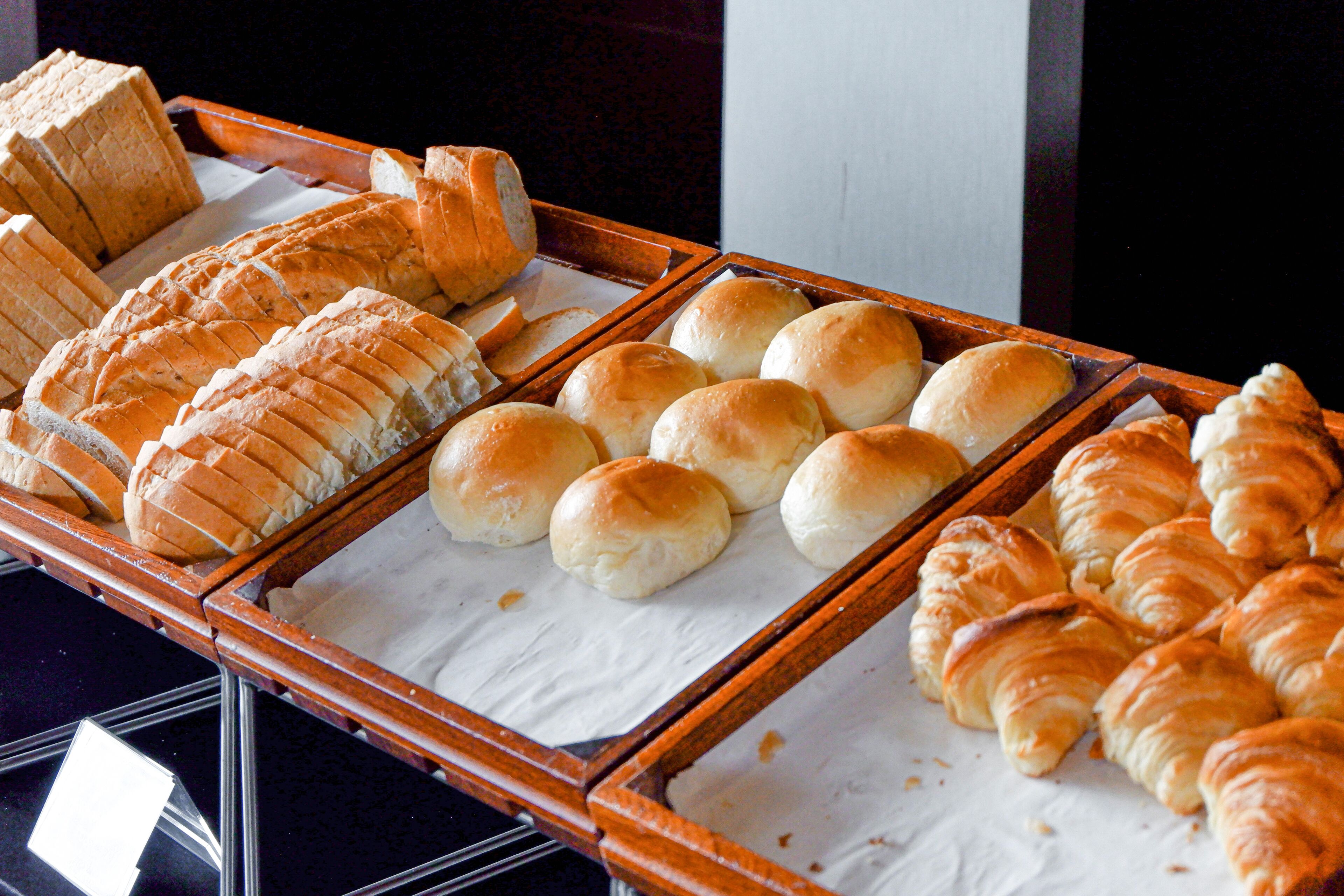 Une variété de produits de boulangerie est exposée, notamment du pain, des petits pains et des croissants.