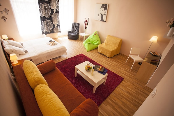 A modern hotel room with a bed, a sofa, a coffee table, and a chair. - Lidicka Apartments (Prague)