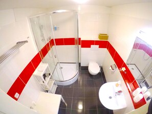 A bathroom with a glass-enclosed shower, a white toilet, and a sink with a mirror. - Lidicka Apartments (Prague)