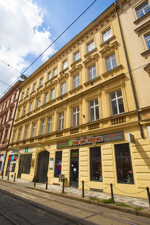 A yellow building with a storefront labeled "Café Con Tumán". - Lidicka Apartments (Prague)