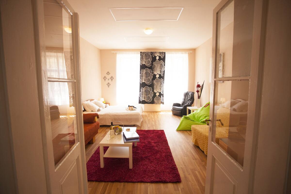 A modern living room with a sofa, a coffee table, and a window with patterned curtains.
