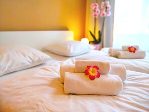 A neatly made bed with rolled towels and a decorative flower. - Lidicka Apartments (Prague)