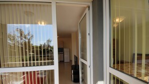 Eine moderne Wohnung mit einer Schiebetür zum Balkon, einer Küchenzeile und einem Essbereich mit Tisch und Stühlen.