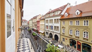 A narrow street with buildings on either side, a checkered floor, and a balcony with potted plants. - Three Golden Crowns Apartments (Prague)