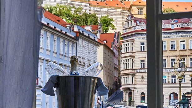 A view from a window overlooking a street with historic buildings, a church spire, and a street lamp. - Three Golden Crowns Apartments (Prague)