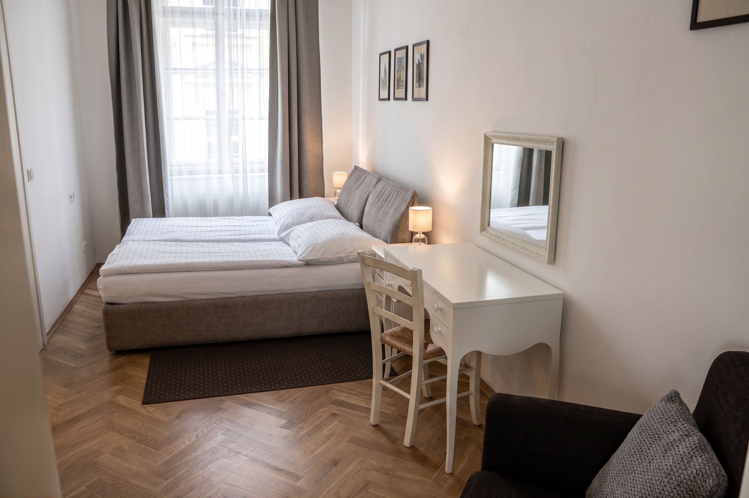 Ein Hotelzimmer mit Doppelbett, Schreibtisch, Stuhl und Spiegel.