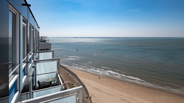 A coastal view from a balcony overlooking a beach with a clear sky.