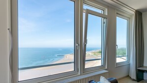 A room with a large window overlooking a beach and ocean.