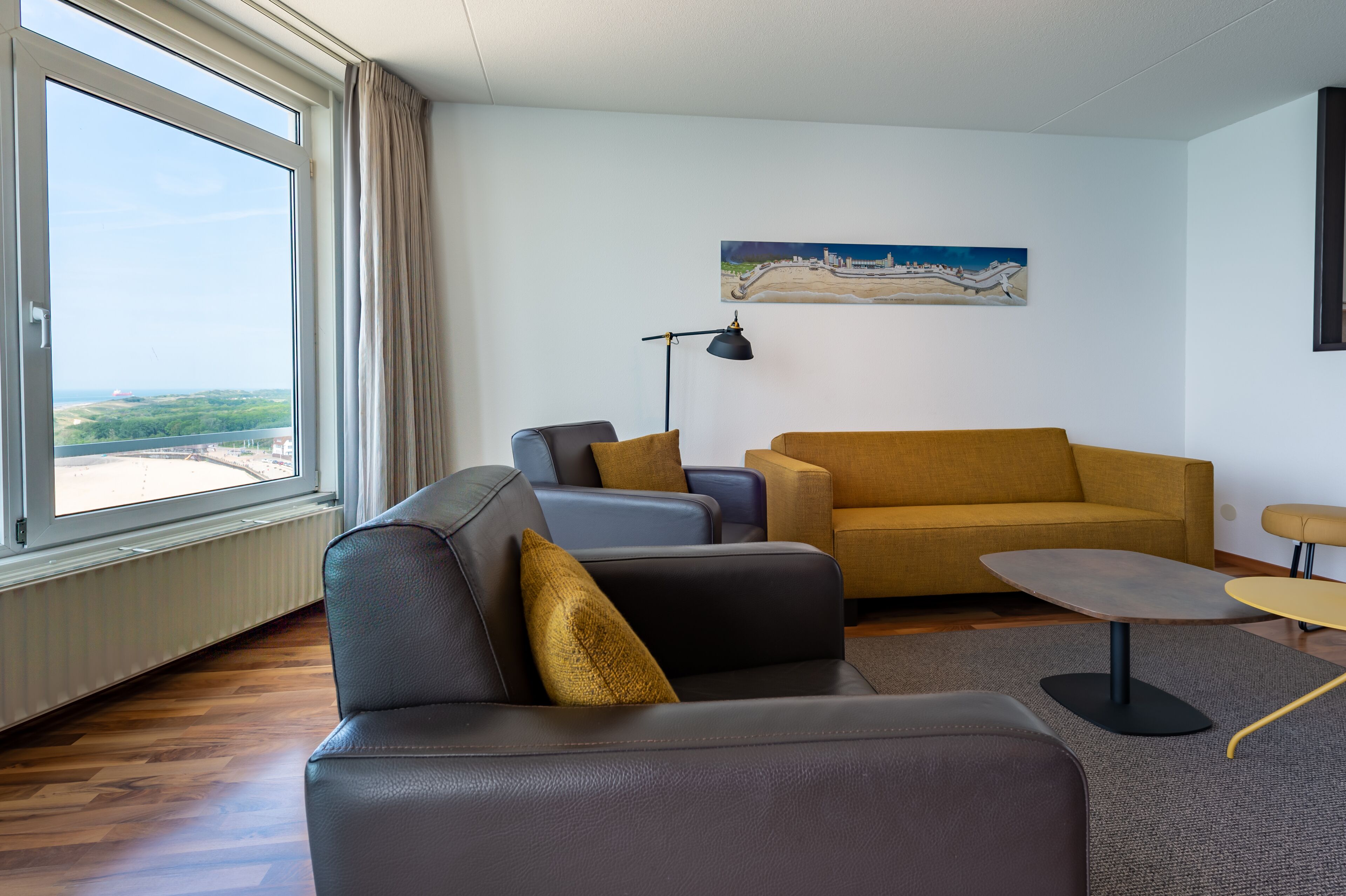 A modern living room with a sofa, armchairs, a coffee table, and a painting on the wall.