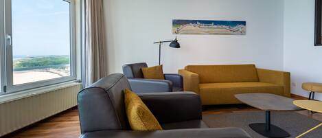 A modern living room with a sofa, armchairs, a coffee table, and a painting on the wall.