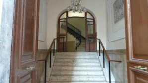 A staircase with wooden railings and a chandelier. - Alex Romano (Rome)