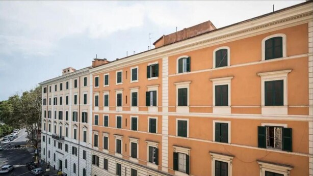 A multi-story building with a consistent architectural style, featuring evenly spaced windows and a flat roof. - Alex Romano (Rome)