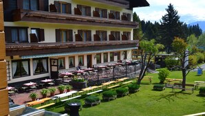 A hotel with outdoor seating, multiple floors, and a garden area. - Hotel Berghof (Berg im Drautal)