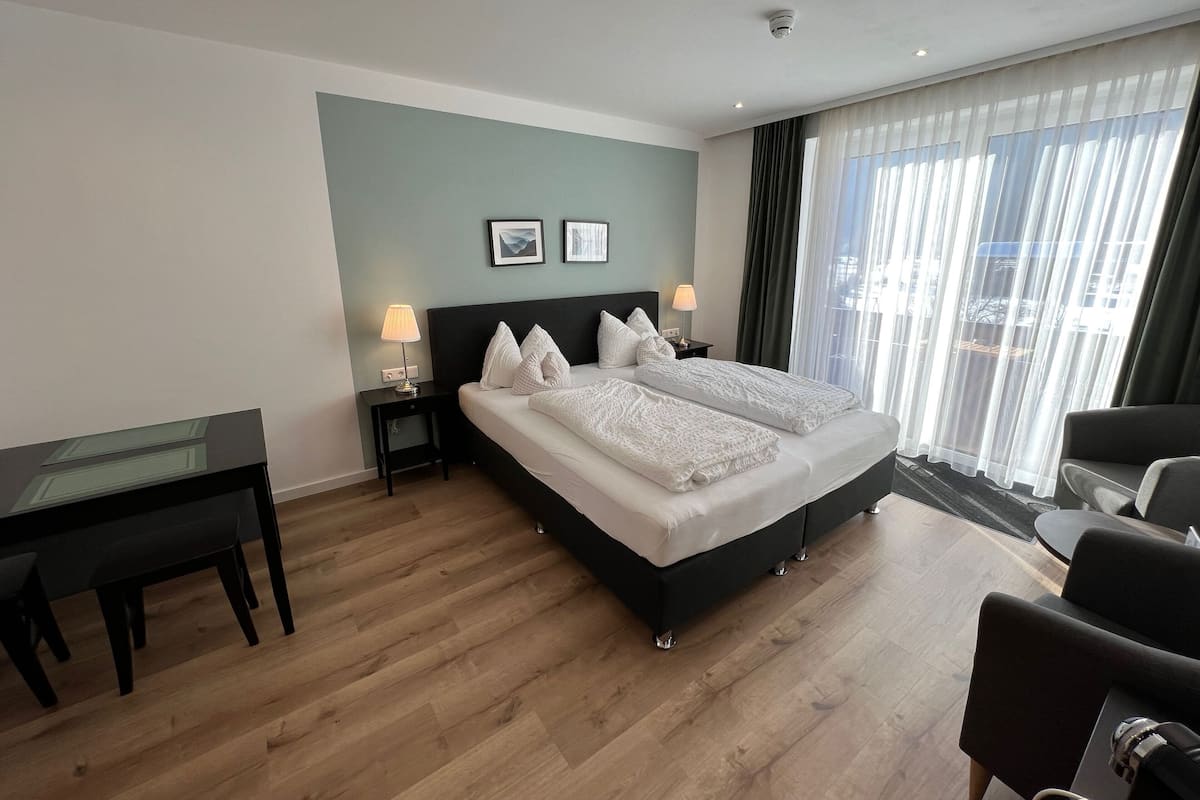 Une chambre d’hôtel avec un grand lit, deux tables de chevet avec des lampes, un bureau et une chaise.