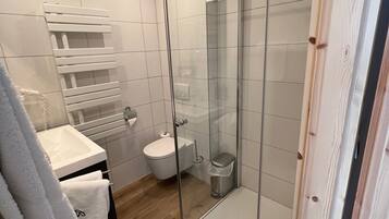 Ein modernes Badezimmer mit einer gläsernen Duschkabine, einem weißen Waschbecken und einer Toilette.