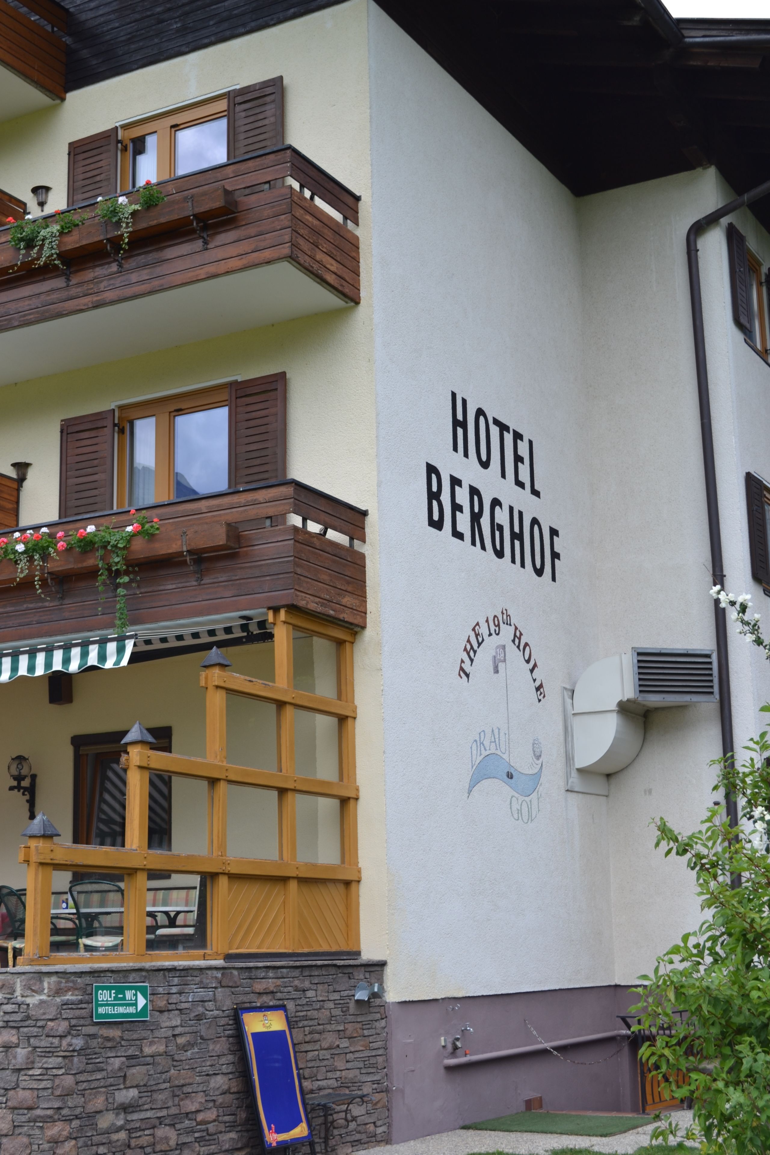 Ein Hotel namens "Hotel Berghof" mit einem Schild, das "The 19th Hole" anzeigt, und einem Golfschild.