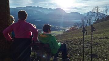 A group of people sitting on a bench overlooking a mountainous landscape.