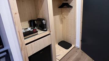 Une pièce de taille modeste, dotée d’un bureau intégré, d’une armoire noire et d’un tapis noir sur le sol.