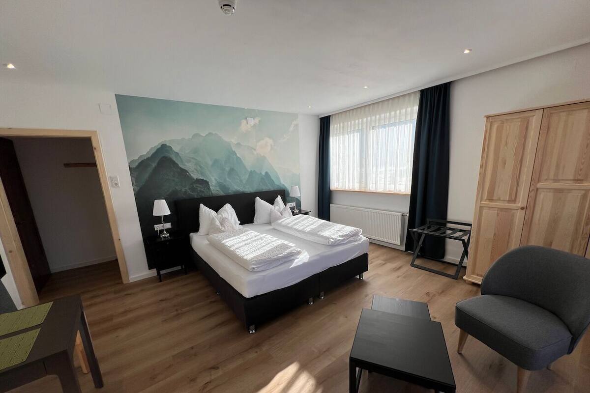 Une chambre d’hôtel moderne équipée d’un lit double, d’un bureau, d’une chaise et offrant une vue sur les montagnes par la fenêtre.