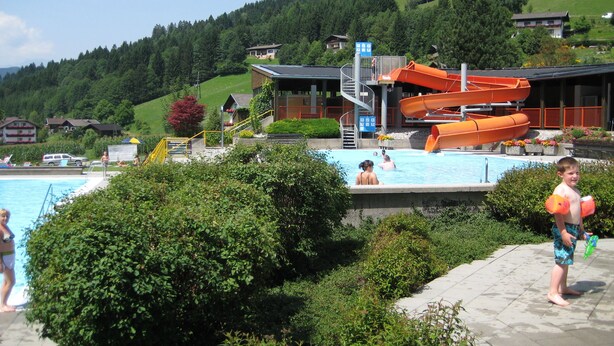 A swimming pool with a water slide and a lifeguard tower. - Hotel Berghof (Berg im Drautal)