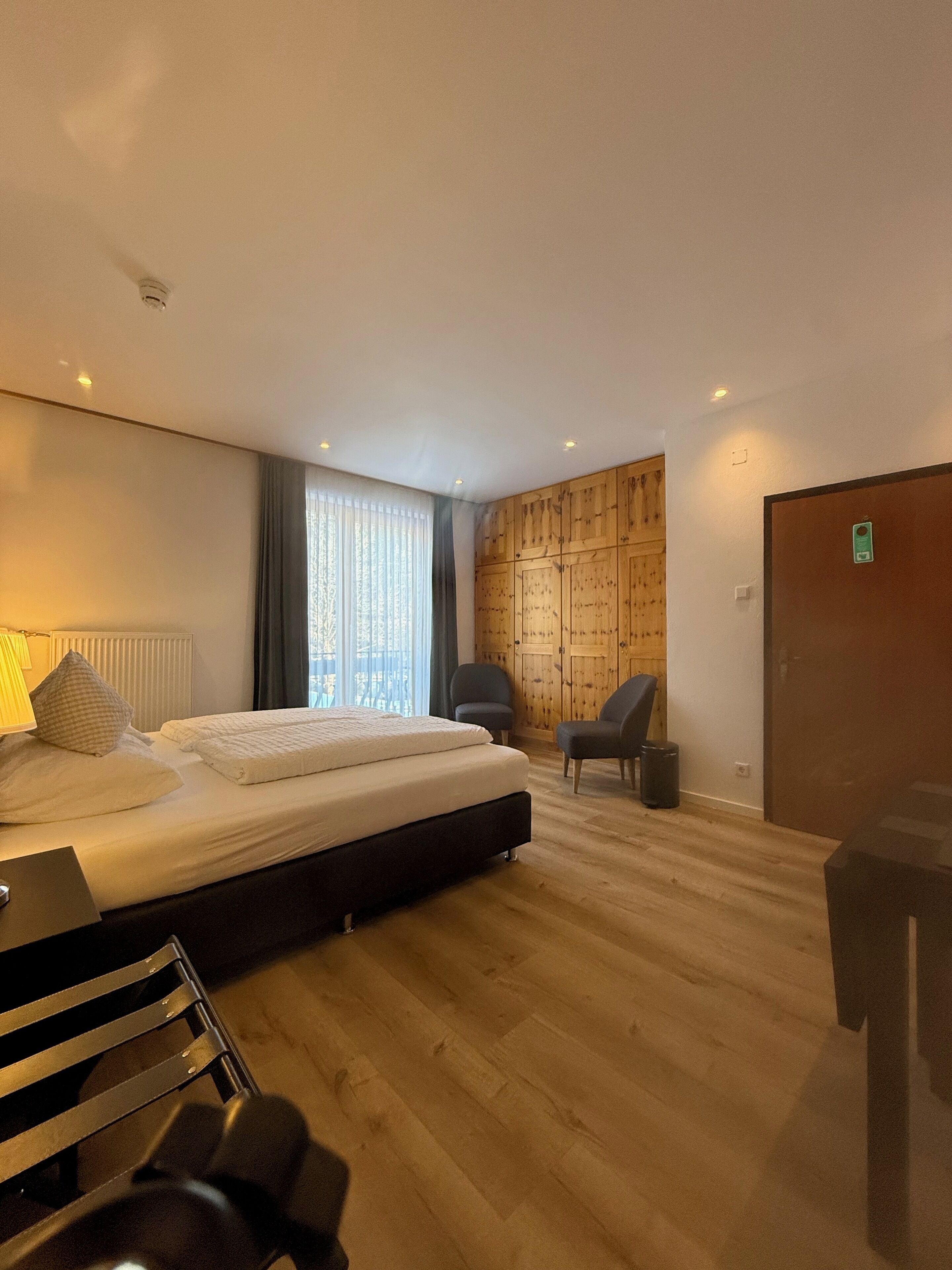 Une chambre d’hôtel moderne, dotée d’un grand lit, d’un bureau, d’une chaise et d’une armoire.