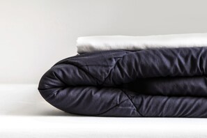 A neatly folded dark-colored pillow on a white surface. - Sant Jordi Hostels Sagrada Familia (Barcelona)