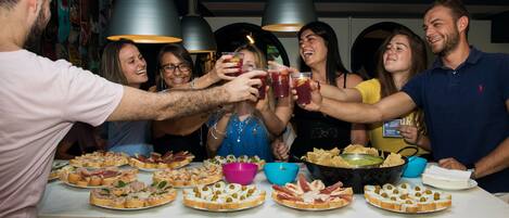 A group of people toasting with drinks around a table with various food items.