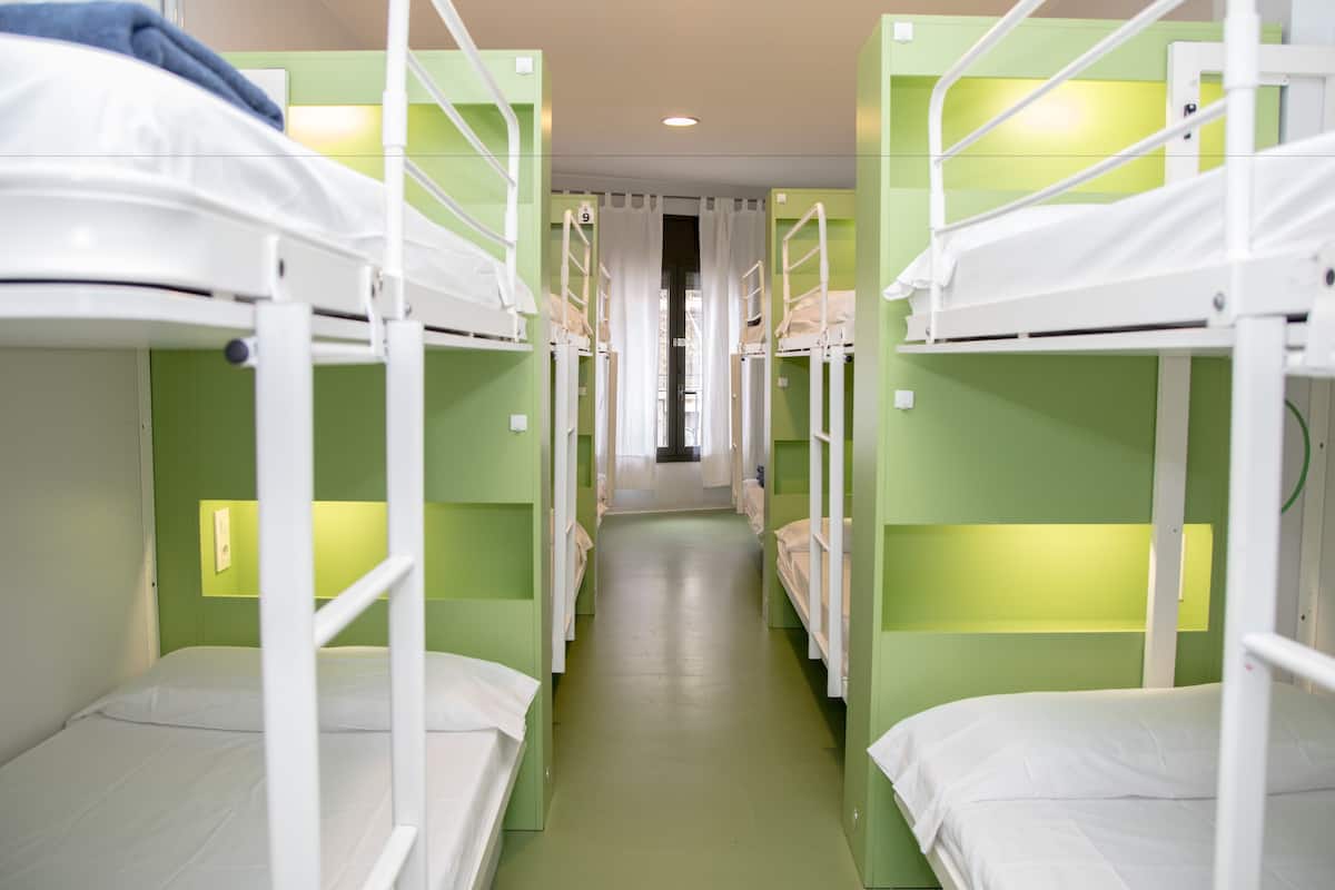 A corridor with bunk beds in a room with green walls and white bedding.