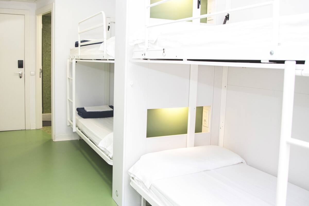 A bunk bed room with a green floor, white walls, and a door.
