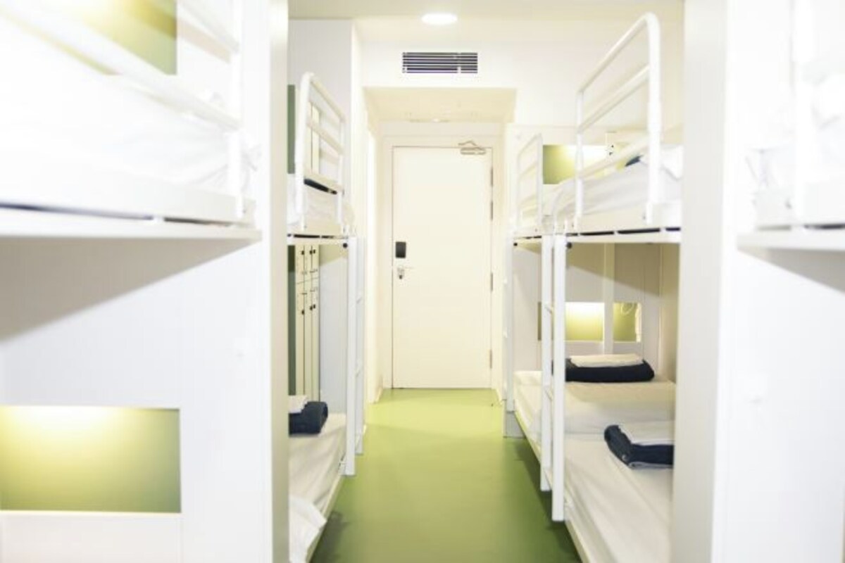 A corridor with bunk beds, a door at the end, and a green floor.